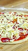 Half ready pizza with cheese, mushrooms, bakon and tomato souce. Pizza ready to be baked in an oven. Food concept. Vertical video