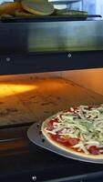 Freshly Prepared Pizza on a Wooden Table in a Cafe. Appetizing hot pizza close-up on the background of the interior of a modern restaurant. Vertical video