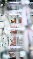 Woman trying glasses in optical store. Vertical video