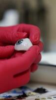 Ophtalmologist holds plastic eyeball in hands. Detailed model of eye. Selective focus on hands in red latex gloves. Vertical video