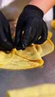Fried meat stuffing is put and rolled into yellow thin pancake. Chef makes stuffed crepes handmade. Close up. Vertical video