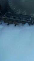 Five connected pipes producing heavy thick white smoke. Granary complex premises and tanks from aerial perspective on grey winter day. Vertical video