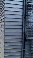 High metal rectangular premise emitting thick grey smoke. Going up along the one of the constructions at modern silo complex. Vertical video