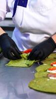 Thin pancakes with herbs are rolled with salmon and cottage cheese. Cook in black gloves puts the fish stuffing into crepes. Vertical video