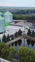 Flying above the modern elevator plant territory. Car park, artificial pond and railways locating at the industrial zone. Vertical video
