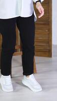 Model jumping high to show white spot shoes. Demonstrating comfortable footwear for everyday activity. Folding screen and tabouret at backdrop. Vertical video