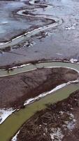 Muddy background. Dirty narrow stream of dried river. Ecological disaster. Natural problems in the world. Muddy water in tortuous river. Top aerial view. Vertical video