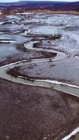 Dried lake. Ecological disaster in environment. Global warming. Tortuous river on dirty background. Motion camera back. Aerial view. Vertical video
