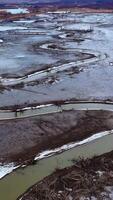 Tortuous river in muddy place. Ecological problems with water. Global warming. Narrow stream from dried river. Nature in danger. View from above. Vertical video