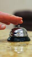 Calling the receptionist. Hand of a tourist in the reception of a hotel presses the bell button. Close-up. Vertical video