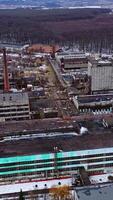 Empty broken industrial plant. Old factory near the forest. Flight over the ruined place after the military actions. Aerial view. Vertical video