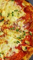 sabroso Pizza en restaurante. Fresco redondo Pizza con queso y verde coles en parte superior giratorio en un de madera tablero en un mesa. Listo Pizza sin uno parte parte. de cerca. vertical video