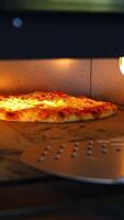 Pizza en horno. horneando Pizza. el cocinero es torneado caliente Pizza con un espátula en un cocina. proceso de Cocinando Pizza en pizzería. sabroso cocina. vertical video