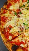 delicioso Pizza. Listo Pizza con Derretido queso giratorio en un mesa en pizzería. bien horneado Pizza en un restaurante. de cerca. vertical video