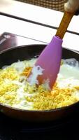 Cooking food in a frying pan. Chef is frying tasty dish in white sauce and mixing it with a scapula. Cooking delicious meal in a restaurant. Vertical video