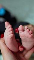 Mutter ist nehmen ihr Kinder Füße im Hände. wenig Baby ziehen um winzig Zehen zu vermeiden kitzelt. verschwommen Hintergrund. Vertikale video