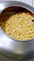 Corn snack sticks being sprayed with sweet syrup in the rotating tank. Snack production at modern food factory. Vertical video