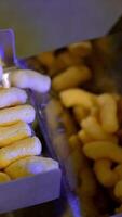 Light crispy corn sticks being pushed on the conveyor belt. Maize snacks production at factory. Vegetarian food concept. Vertical video