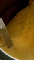 Centrifuge mechanism rotating and mixing yellow stuff. Maize snacks production at food factory. Close up. Vertical video