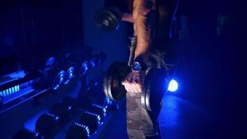 Athletic young man with dumbbells. Muscular man working out in gym doing exercises with dumbbells at biceps video