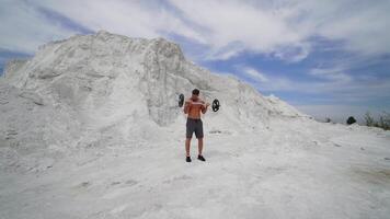 Man with weight training on nature. Handsome man doing biceps lifting on nature video