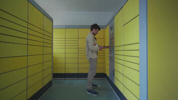 Man at packing station using screen and holding box for self shipment. Parcel pick-up point, parcel delivery, package delivery. Yellow self-service post terminal machine. Deposit parcel for storage. video
