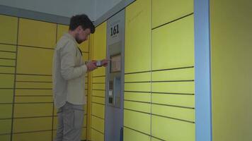 Man uses yellow packing station to send package by self-service. German package and delivery service terminal. Sender types tracking label at yellow packing center in Deutschland and send packet. video