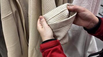 A persons hands holding beige waffle texture fabric in a store, related to shopping and home decor video