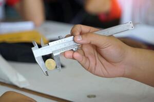 Hand holding Vernier calipers to measure the diameter of coins. Concept of science laboratory, precision measuring instruments, measurement photo