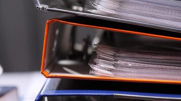 Overflowing office binders stacked high, suggesting a busy administrative environment with a focus on organization and paperwork management. close-up colored binders are stacked. video