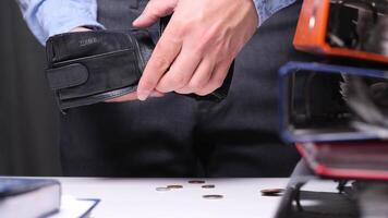 Struggling office worker shakes out last coins from empty wallet, highlighting poverty and financial stress. Businessman dropping last coins from empty wallet at office desk video