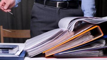 close-up man opened a folder with documents and reads a document. Office worker holds glasses in his hands and studies archival documents from an open binder folder. Concept of heavy office work video