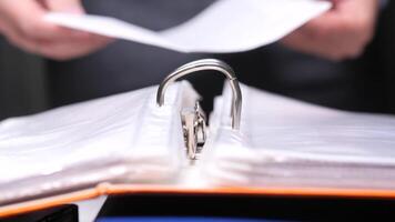 Office worker takes a document out of an archive binder folder. Businessman browsing documents in binder filled with clear plastic sleeves. video