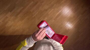 pov first person view Man on a wooden floor joyfully uses a red money gun to make cash rain, celebrating success and wealth with excitement and abundance. Perfect for showcasing the fun video