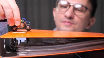 Businessman is holding a toy motorcycle above an orange folder, representing procrastination, work-life balance, and playful approach to business. video