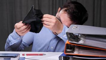A man, upset by the lack of money, clutches his head. The man has run out of money. Office worker showing empty wallet, struggling with financial problems, having no money, facing bankruptcy video