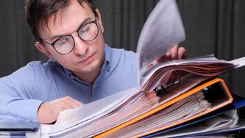 close-up Office worker checking financial documents and searching information in archive folders, sitting at desk and working with paperwork. Heavy routine monotonous office work with documents video