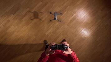 firs person view pov Person using a remote control to pilot a drone indoors, hovering above a wooden floor, providing a unique perspective on drone operation video