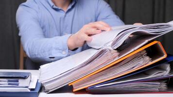 close-up Office worker searches through a stack of documents, showing the chaos and stress of a busy workplace. concept of heavy office work. Backlog at work. overtime in the office video