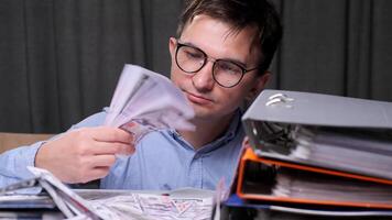 a satisfied businessman, entrepreneur, office worker holds a wad of banknotes in his hands. Businessman counting us dollars surrounded by office binders, showing finance and wealth themes video