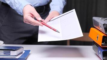Confident office worker showing where to sign on document, emphasizing importance. Neat desk, binders, notebook convey professionalism video