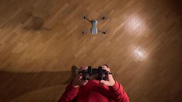 pov first person view Man piloting drone indoors with remote control, hovering over parquet floor. Experience technology, entertainment, and skill in maneuvering quadcopter with precision video