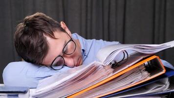 Exhausted office worker sleeps on a stack of documents, overwhelmed by work stress and fatigue. Balancing work and mental health is a challenge video