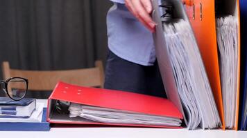 men stack binders with documents on the desk. Concept of archive of documents. Worker organizes archive folders on a desk in a busy office, creating an efficient workspace with stacks of documents video