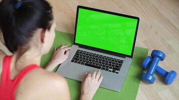 A woman is using a laptop with a green screen, ideal for digital content creation, E-commerce, remote work, online tasks, and showcasing technology for marketing and creative projects video