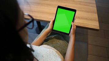 A woman using a tablet with a green screen, ideal for digital content creation, E-commerce, remote work, online tasks, and showcasing technology and creative projects video