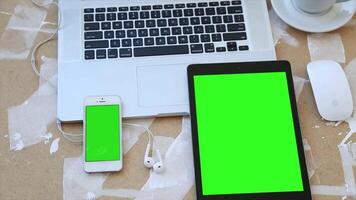 Laptop, Tablet, and Phone with Green Screen on a Table video