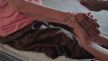 A detailed close-up captures the gentle touch of a child's hands massaging the weathered hands of their elderly parent video