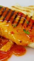 Shawarma or doner kebab on white table poured with souce. Pita roll is made with tortilla, beef, tomato, onion and lettuce. Vertical video