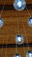 Cozy ceiling with many crystal small balls. Round light bulbs hanging on white wires. Modern design of shiny light lamps. Vertical video